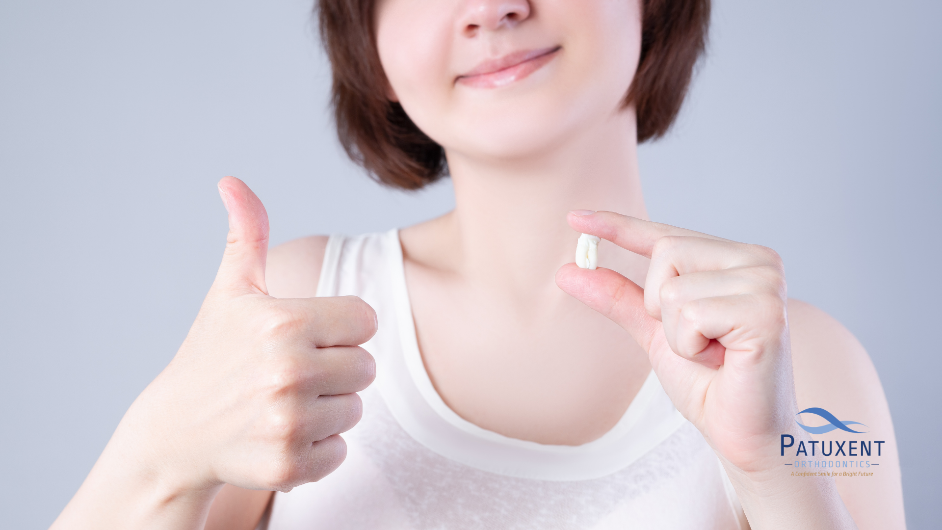 Girl holding wisdom tooth and giving a thumbs-up